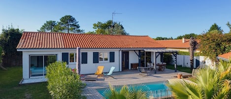 A house with a tiled roof, a swimming pool, and a covered patio area.