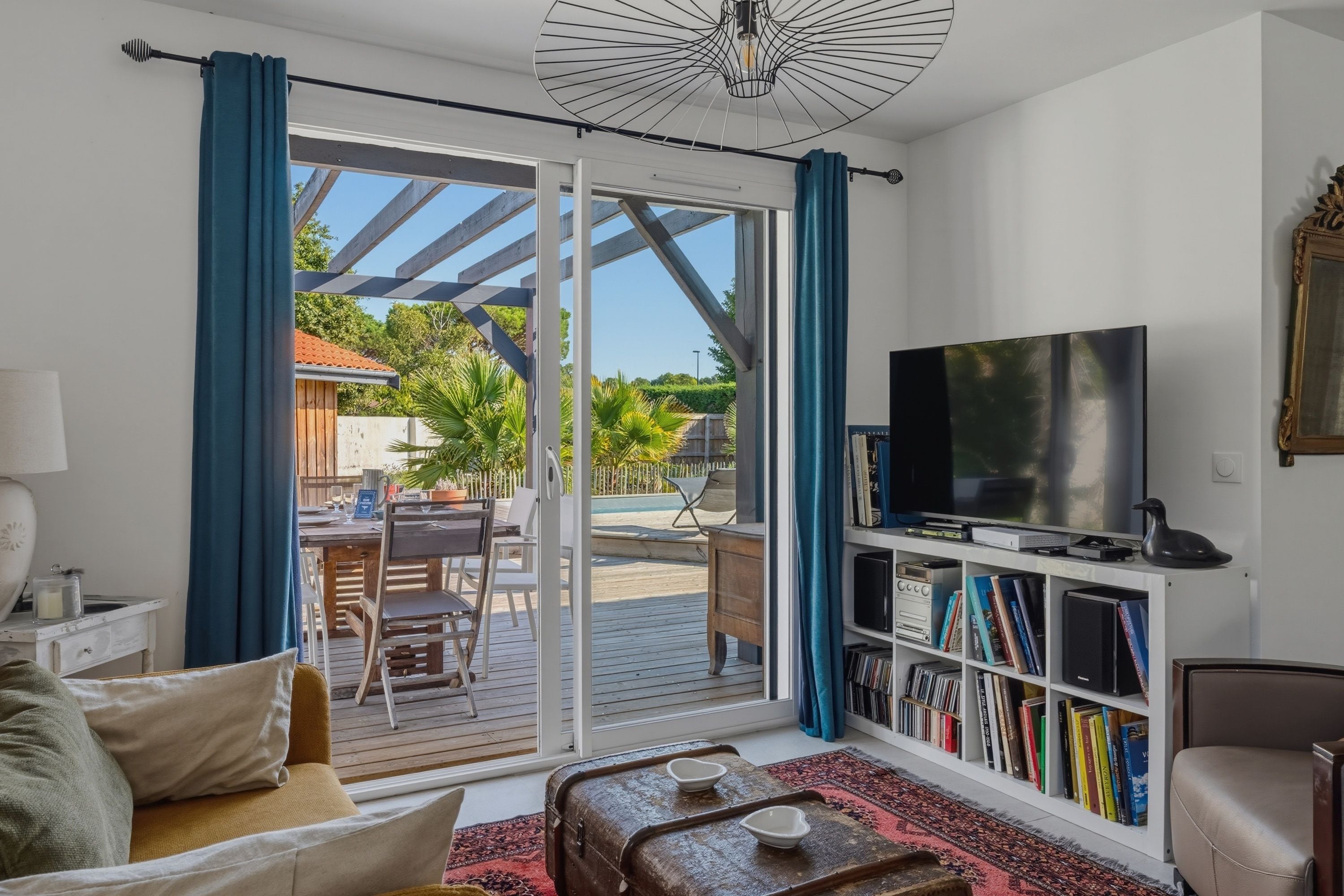 A living room with a television, bookshelf, and a sliding glass door leading to an outdoor area.