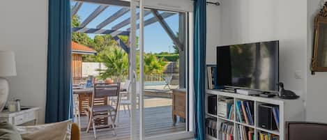A living room with a television, bookshelf, and a sliding glass door leading to an outdoor area.
