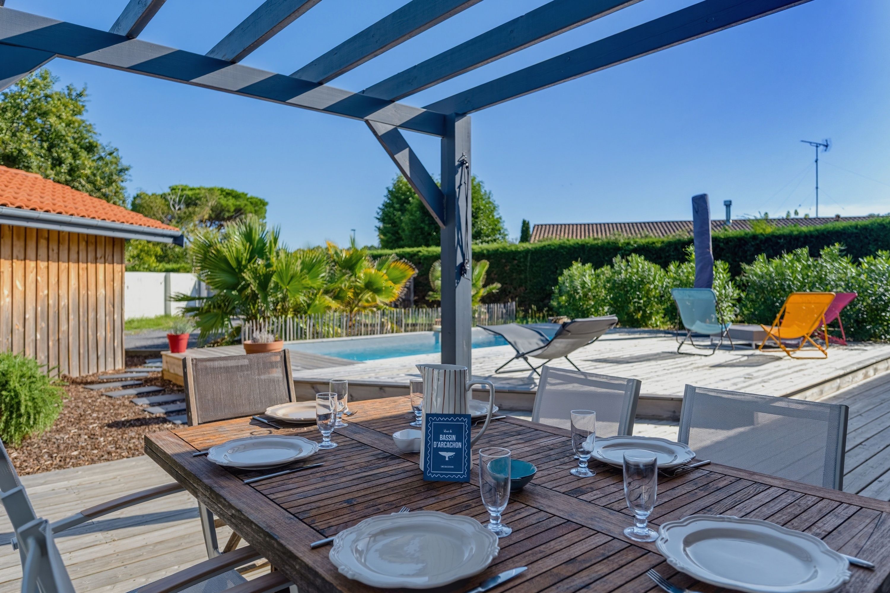 Un espace extérieur aménagé pour les repas, avec une piscine, des chaises longues et une pergola.