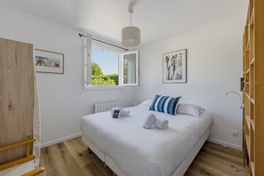 Een slaapkamer met een bed, een raam, een radiator en een deur.