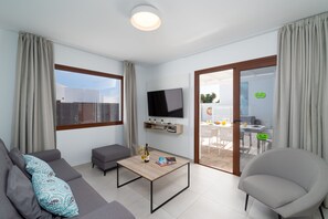 A modern living room with a sofa, a coffee table, and a TV mounted on the wall. - Ereza Villas La Granja 2 (Yaiza)