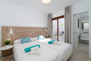 A modern hotel room with a large bed, a bedside table, a small potted plant, and a view of the outside. - Ereza Villas La Granja 2 (Yaiza)