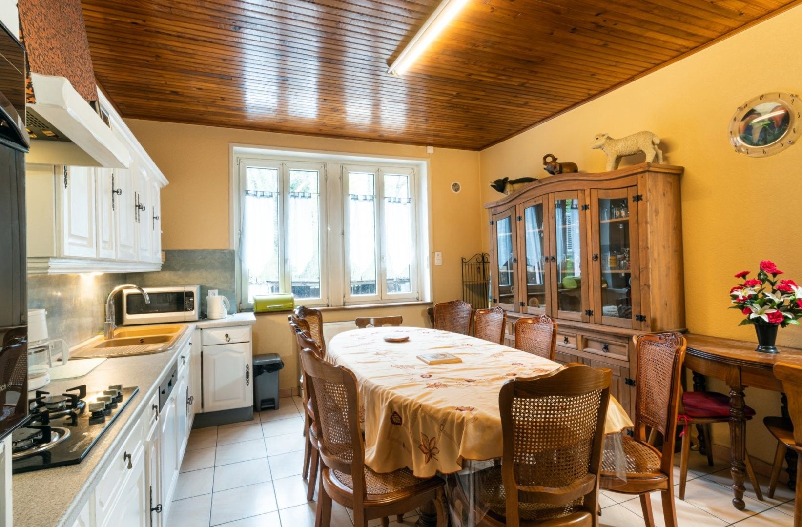 A kitchen with a dining table, chairs, a microwave, and a cabinet.