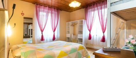 A bedroom with a bed, a dresser, a wardrobe, and a mirror.