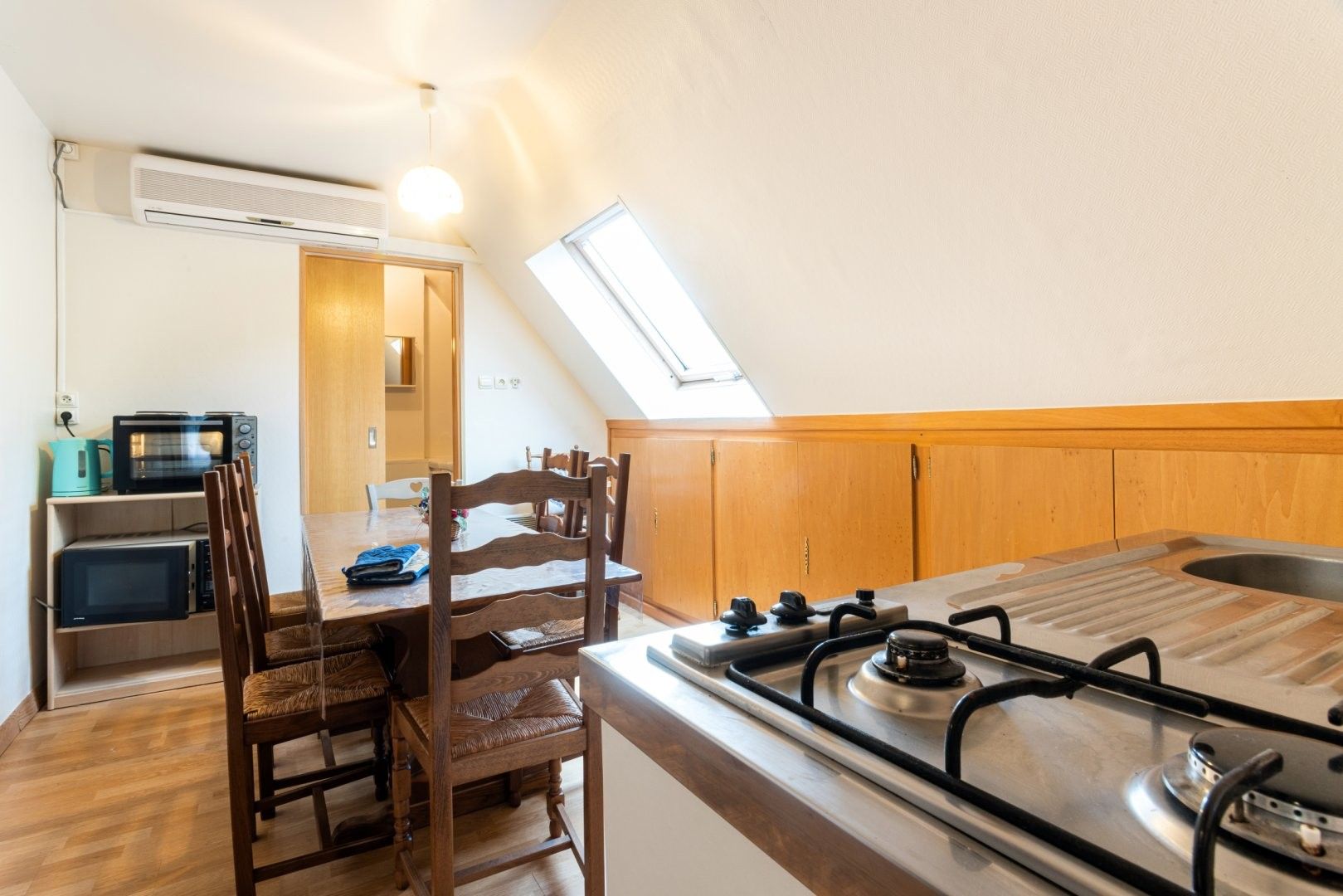 A compact kitchen with a gas stove, wooden chairs, a dining table, and a built-in microwave.