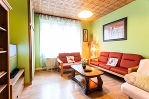 A living room with a sofa set, a coffee table, and a television on a stand. - Gîte “Gîtes du Niederwald” with Shared Terrace, Wi-Fi, and Air Conditioning (Guémar)