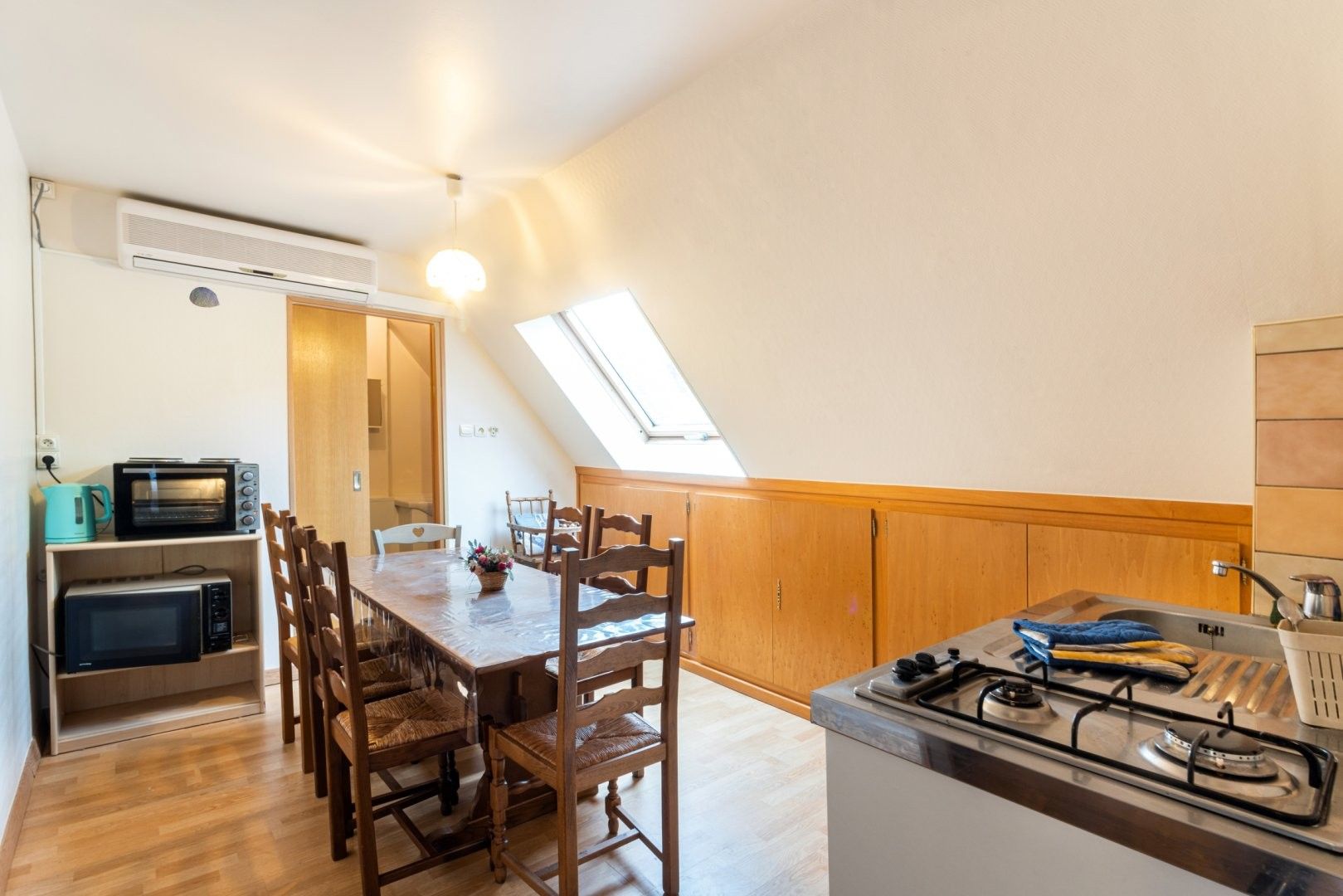 A compact kitchen with a dining table, chairs, a gas stove, and built-in microwaves.