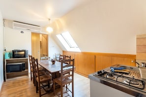 A compact kitchen with a dining table, chairs, a gas stove, and built-in microwaves. - Gîte “Gîtes du Niederwald” with Shared Terrace, Wi-Fi, and Air Conditioning (Guémar)