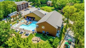 Un hotel con piscina, mobiliario exterior y un edificio grande de varios pisos.