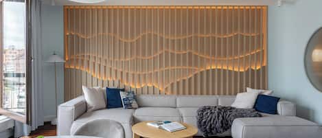 A modern living room with a sectional sofa, a round coffee table, and a decorative wall panel.