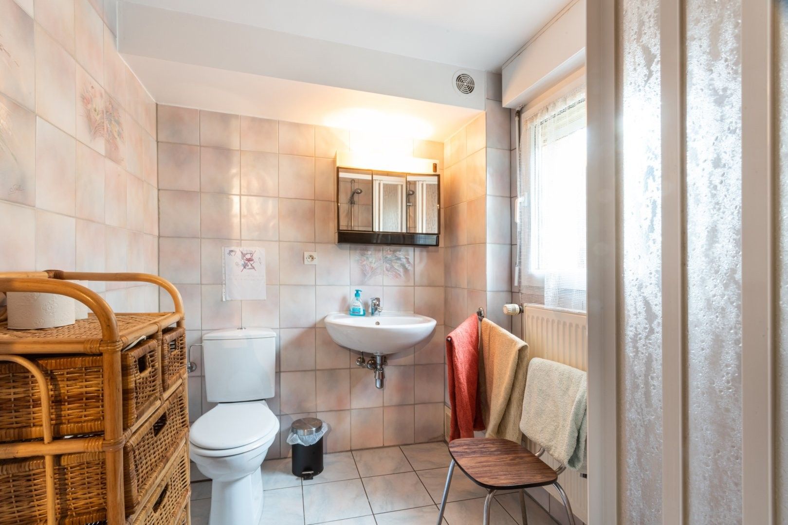 A bathroom with a toilet, sink, and a window with a view.