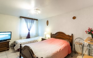 A hotel room with two single beds, a television, a small table with a chair, and a window with curtains. - Bed and Breakfast 'Chambre Susanne' with Wi-Fi (Guémar)
