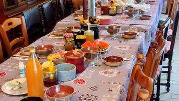 Una mesa de comedor preparada con varios platos, cubiertos y condimentos, rodeada de sillas de madera.