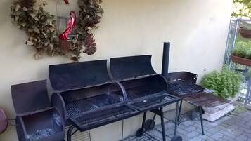 Un espace barbecue extérieur comprenant une table en métal, une cheminée et une guirlande décorative.