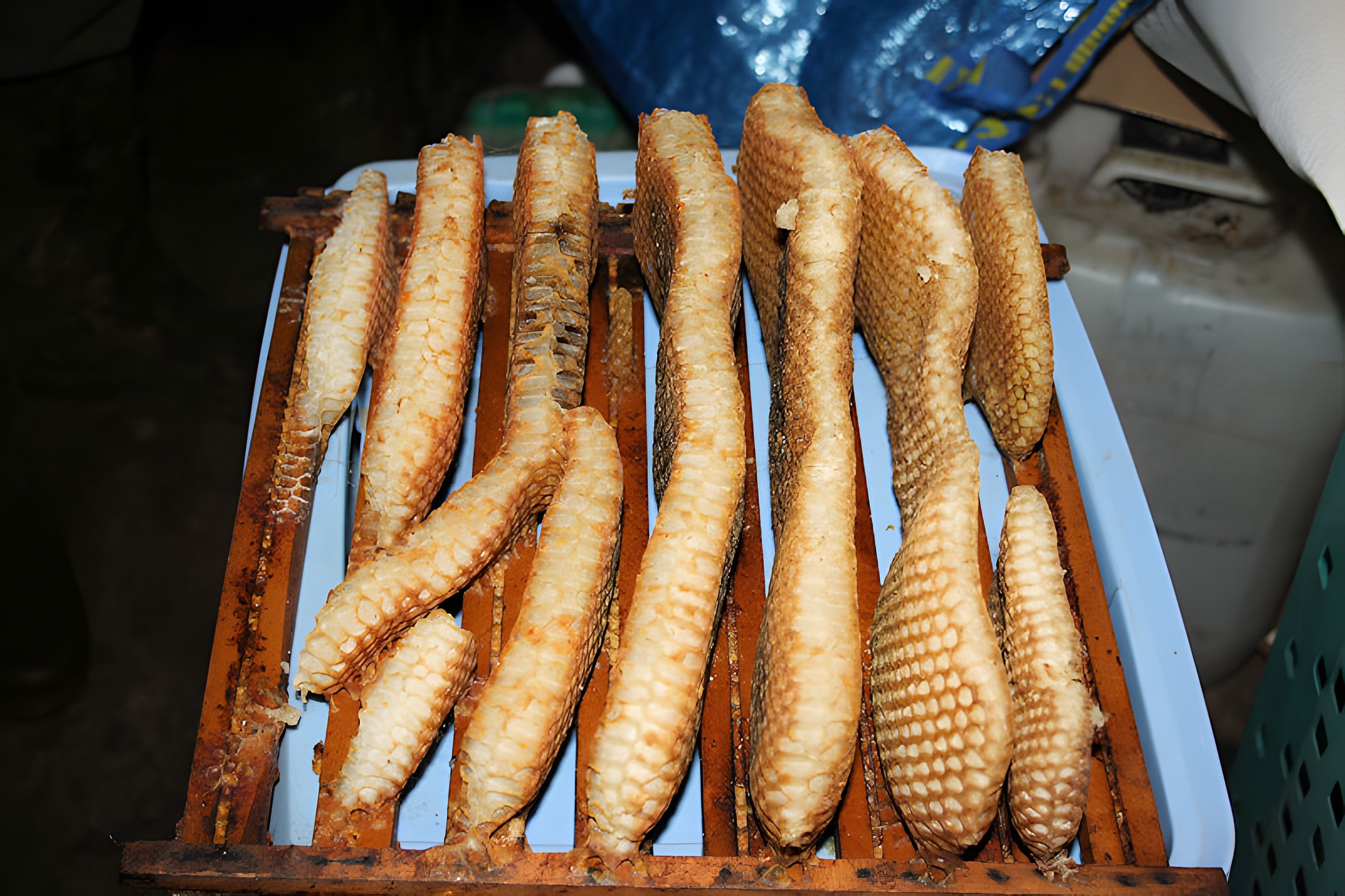A tray of fried fish with a textured skin, arranged in a wooden rack.