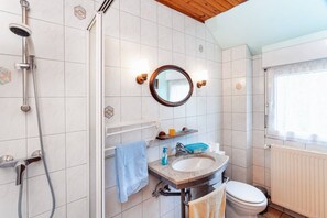 Une salle de bain avec une douche, un lavabo, des toilettes et une fenêtre.