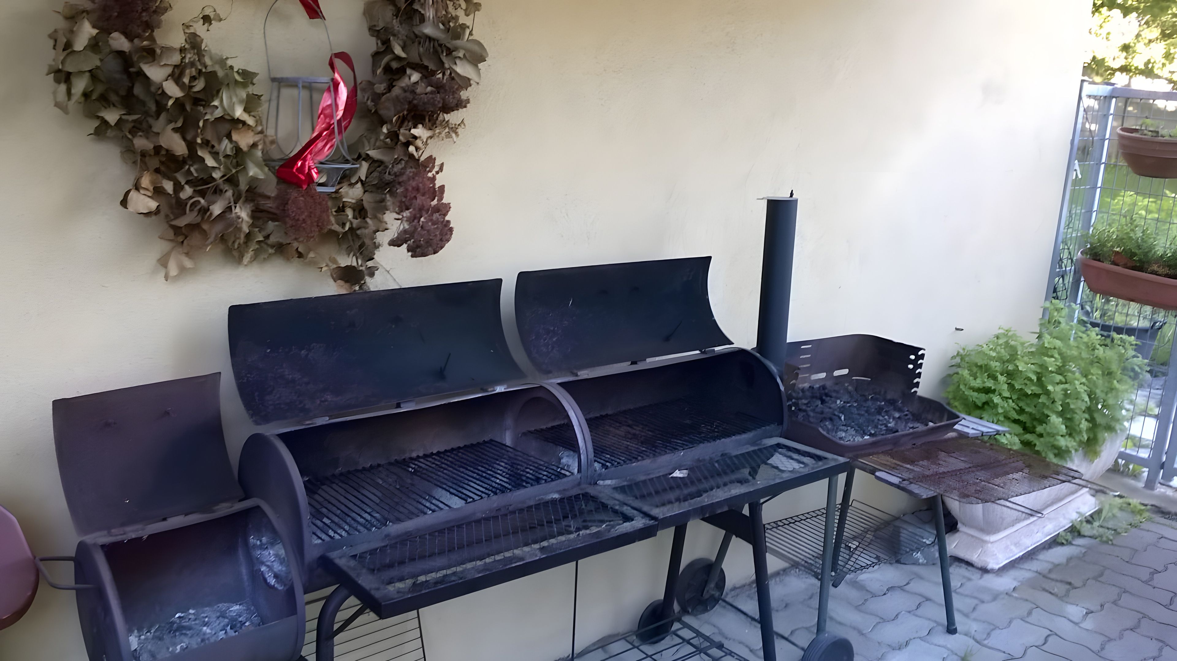 An outdoor grill area with a metal table, a chimney, and a decorative wreath.