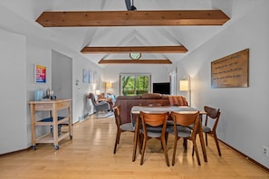 A spacious room with a wooden dining table and chairs, a sofa, and a view of the outdoors. - Fenced Yard | Near Golf & Saugatuck | Hot Tub (Saugatuck)
