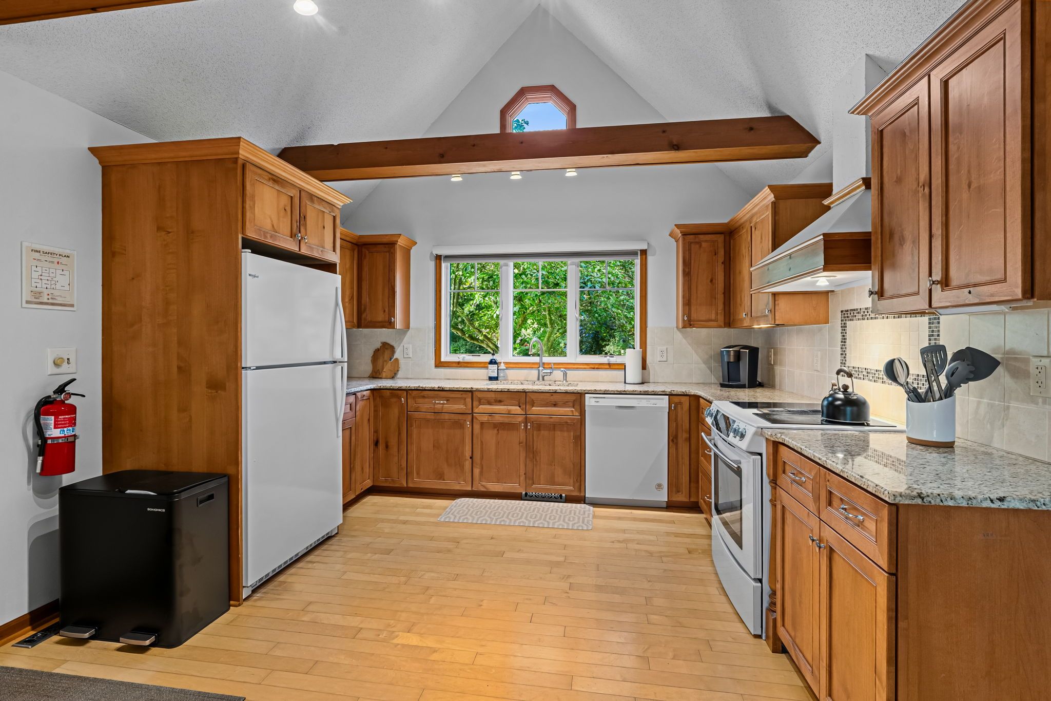 Una cocina con gabinetes de madera, un refrigerador de acero inoxidable, un lavavajillas y una estufa.