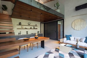 A modern interior with a dining area, a sofa, and a staircase.