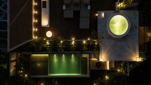 Et tagområde med pool, et cirkulært spabad, træterrasse og et loungeområde med puder.