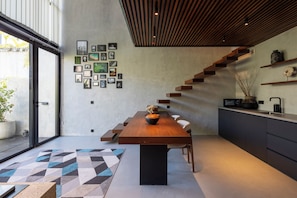 Une cuisine moderne avec un escalier en bois, une table à manger et divers tableaux encadrés accrochés au mur.