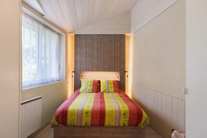 A bedroom with a wooden headboard, a window with sheer curtains, and a bed with striped bedding. - Holiday Home 'Gîte De Christine Amboise Centre' with Private Terrace and Wi-Fi (Amboise)