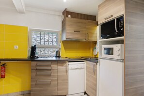 A modern kitchen with yellow and white cabinetry, a Bosch dishwasher, a Samsung microwave, and a window with a view of a rocky landscape.