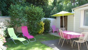A patio with a table and chairs, a yellow umbrella, and a small shed.