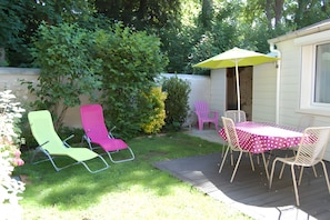 A patio with a table and chairs, a yellow umbrella, and a small shed.
