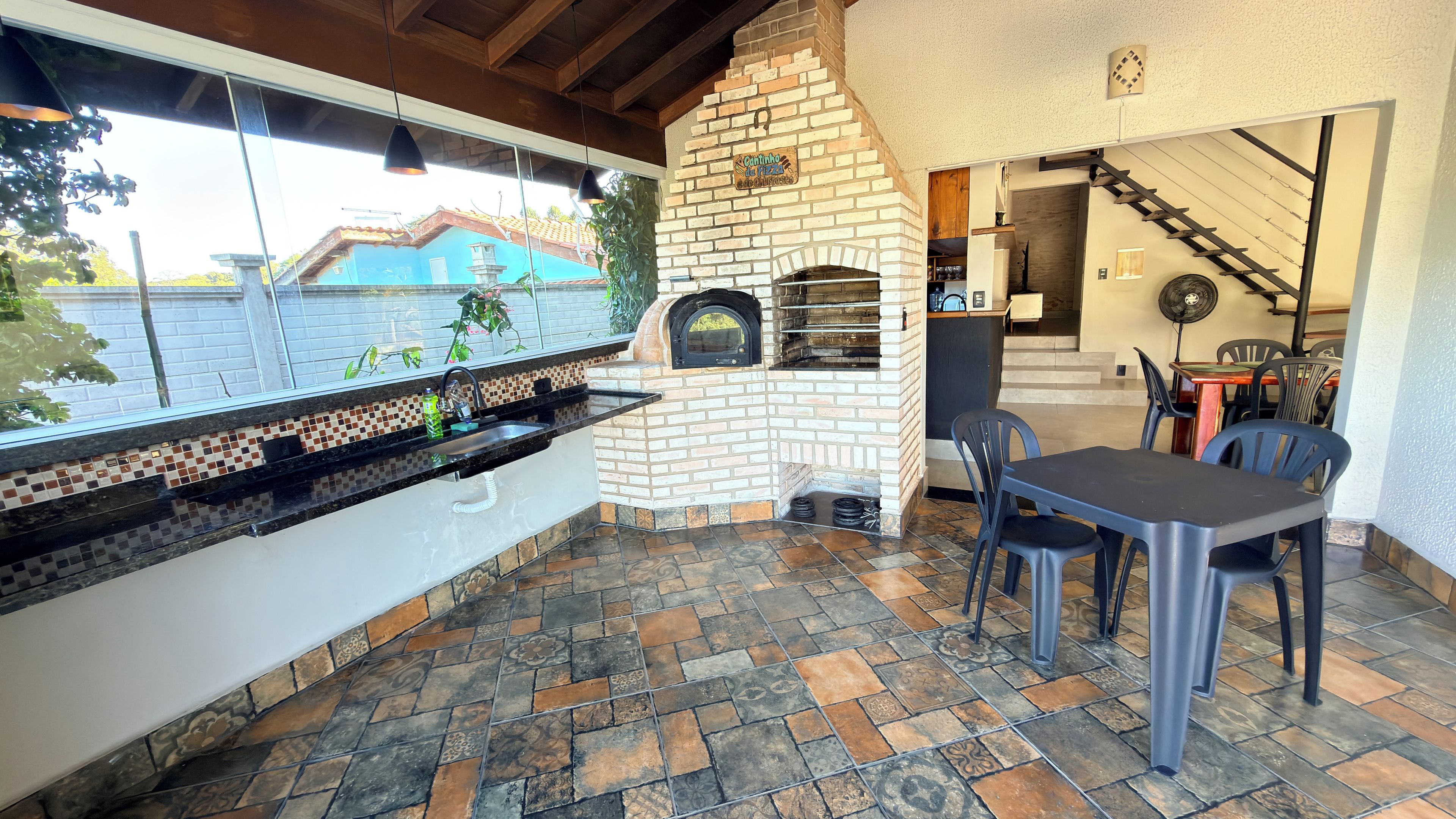 An outdoor kitchen area with a brick oven, a sink, and a dining table with chairs.