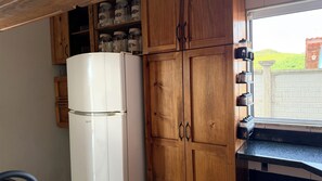 Una cocina con armarios de madera, un refrigerador blanco y una ventana con vistas a zonas verdes.