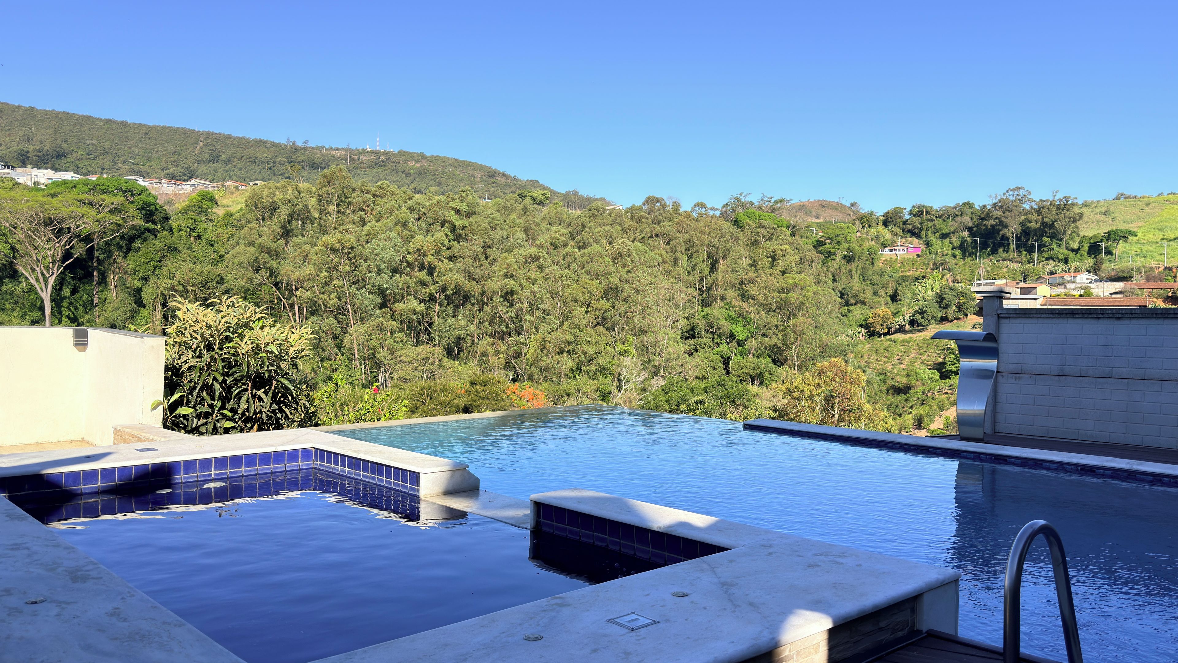 A swimming pool with a view of a forested hillside.