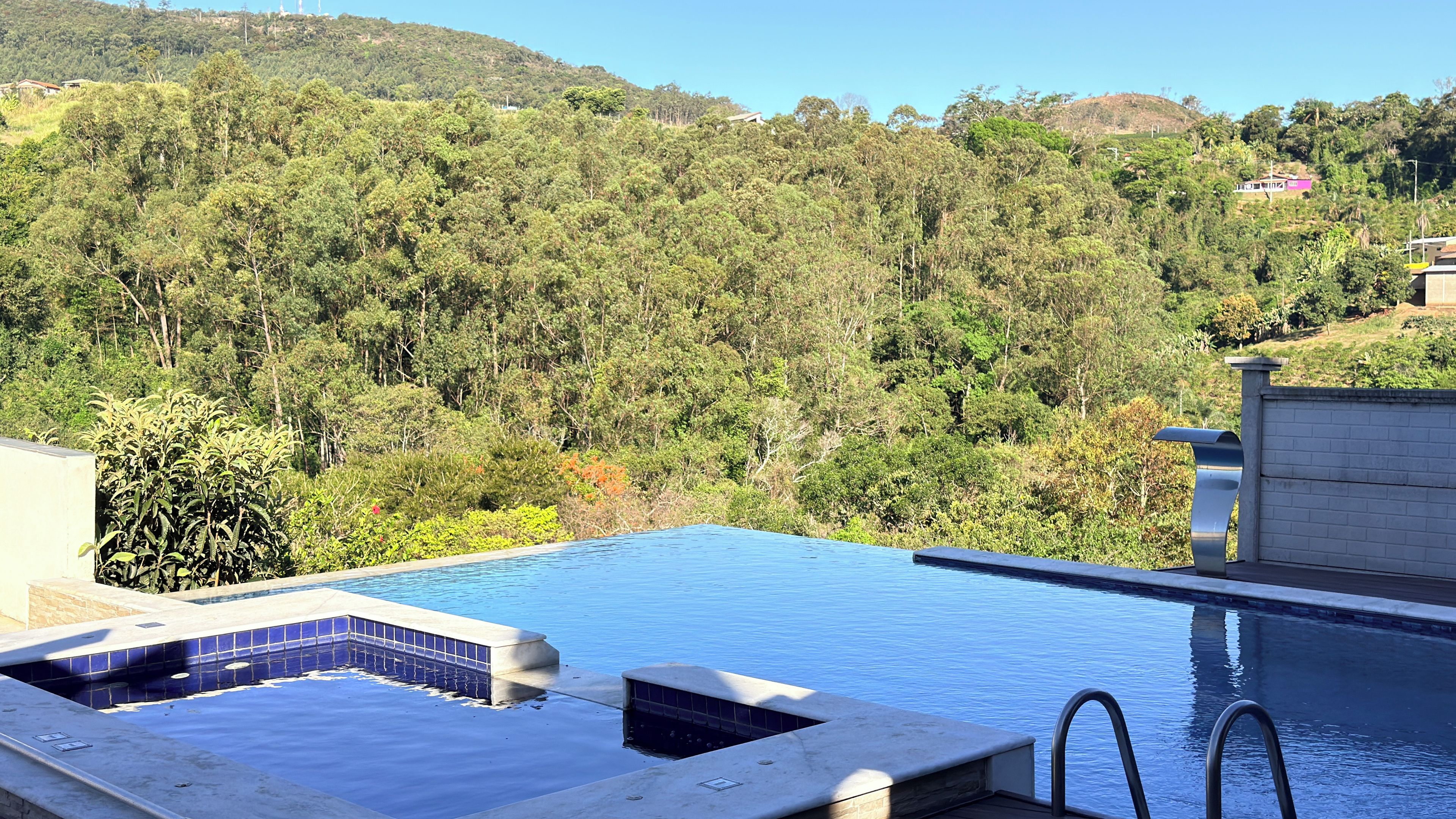 A swimming pool with a view of a forested hillside.
