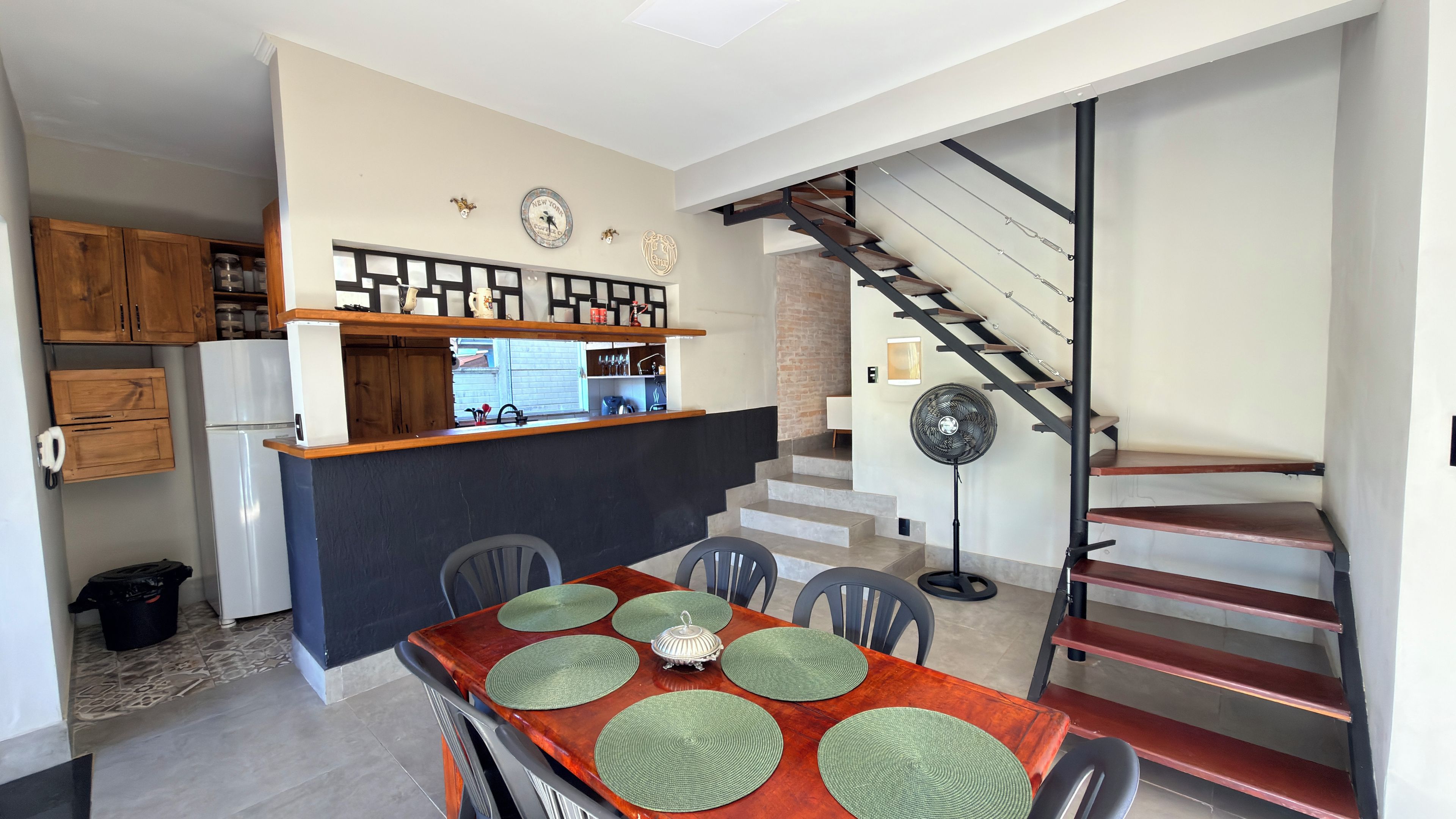 Una cocina moderna con refrigerador empotrado, gabinetes de madera y un comedor con mesa y sillas de madera.
