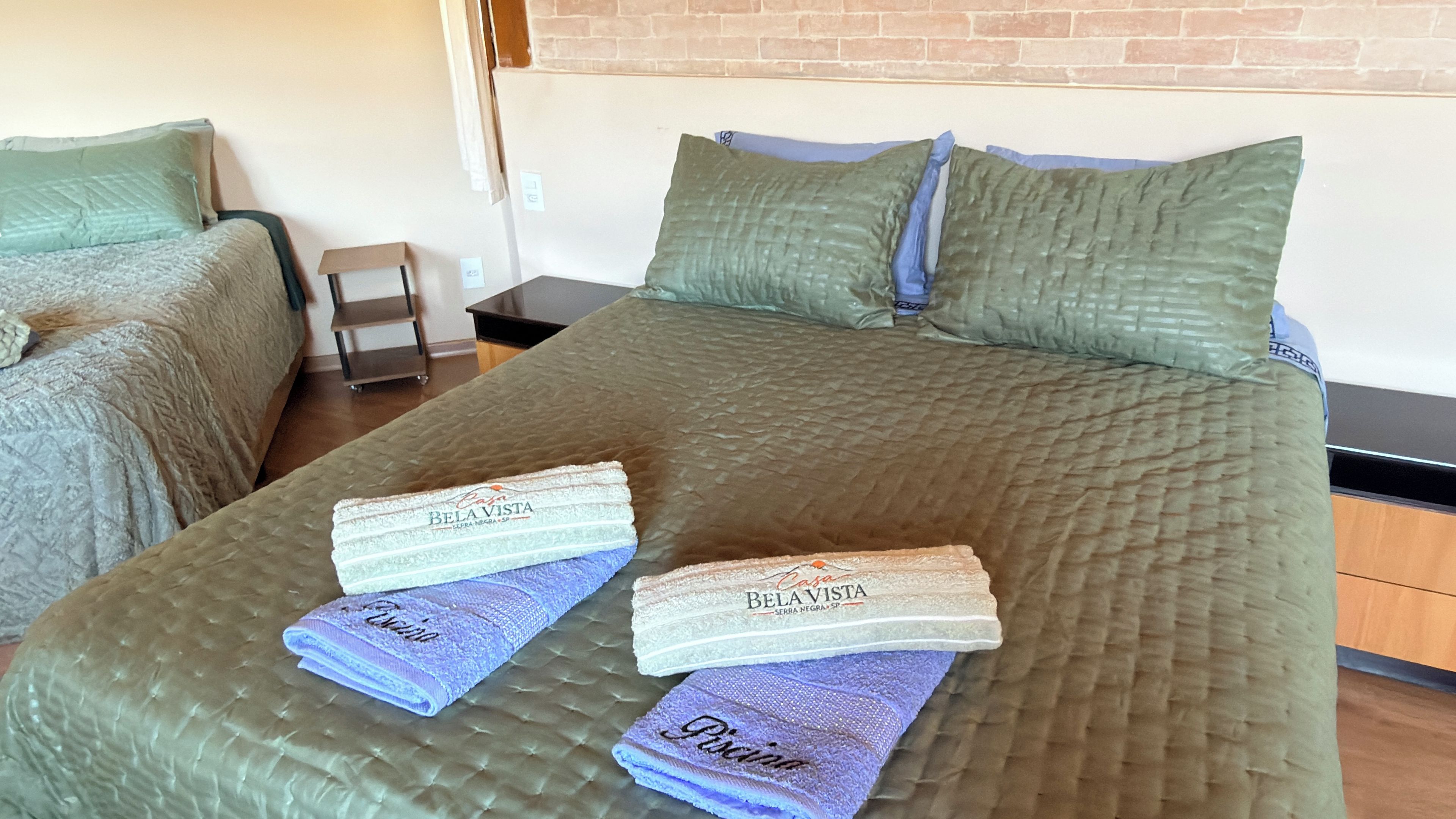 A hotel room with a large bed, two pillows, a nightstand, and a small table.