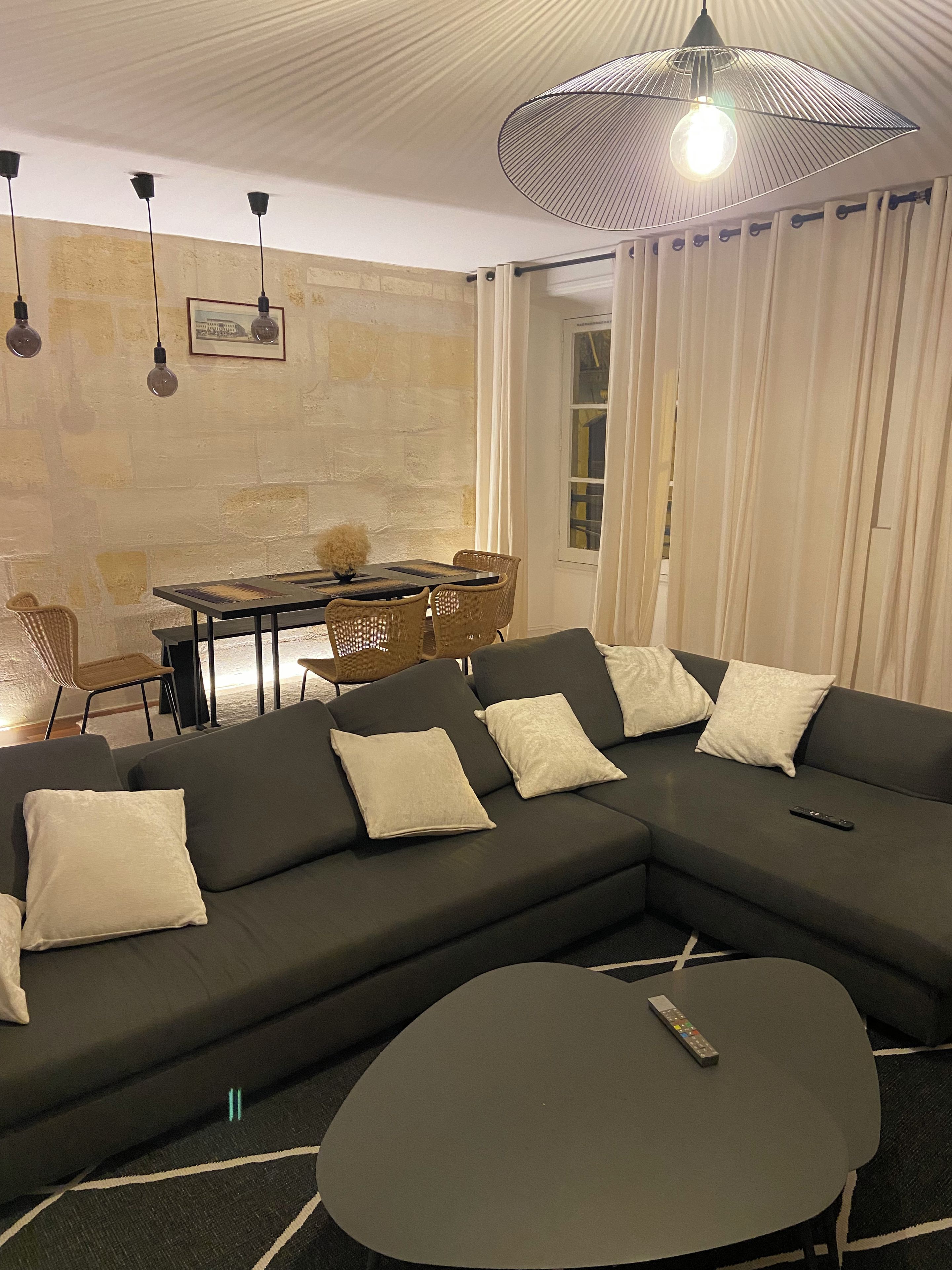 Uma sala de estar moderna com um sofá modular, uma mesa de jantar e um lustre.