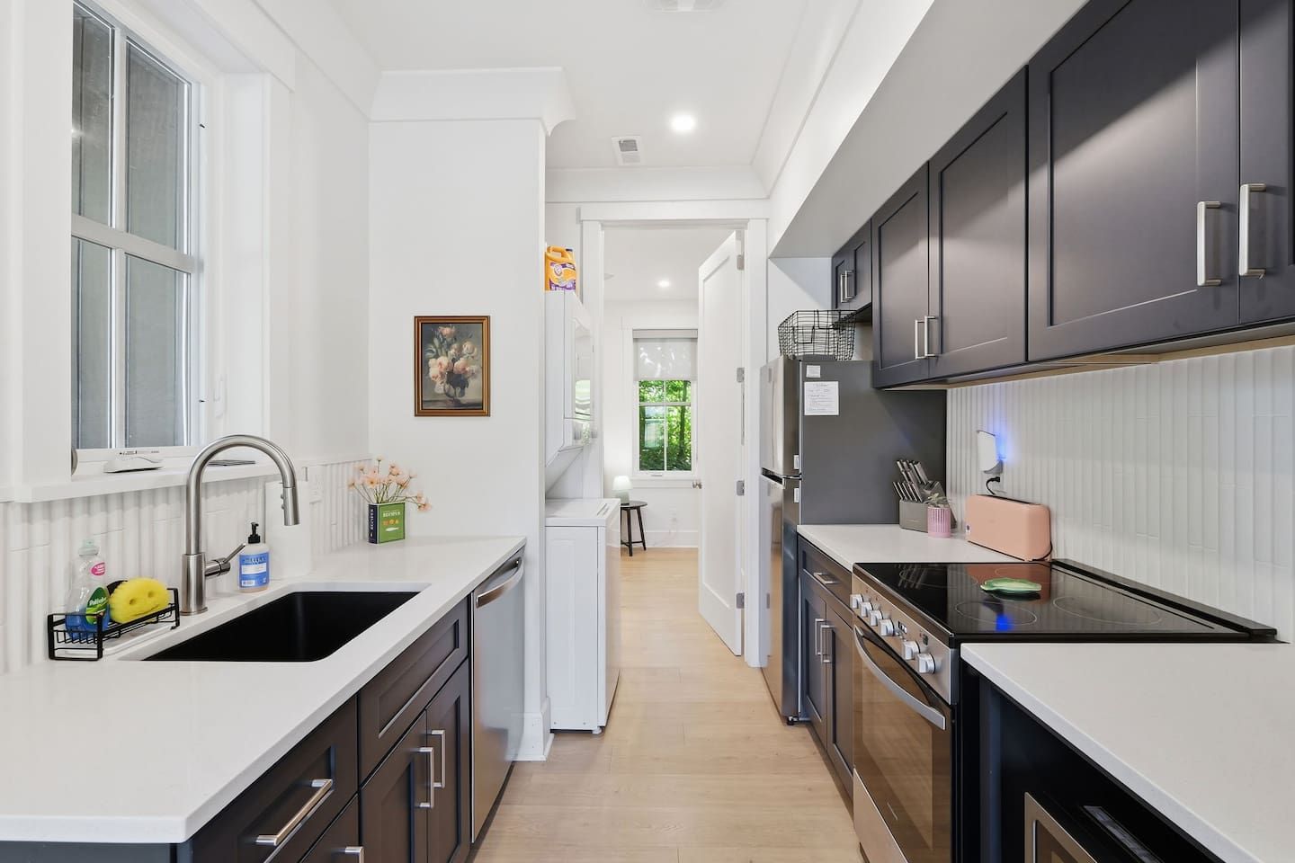 A modern kitchen with white countertops, dark cabinets, and stainless steel appliances.