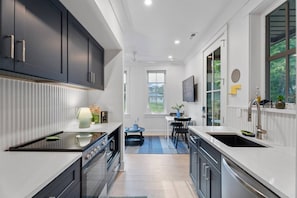 A modern kitchen with dark cabinets, a built-in oven, and a large window. - Downtown Centric, Tucked Away, Fenced, PetsOK (Durham)