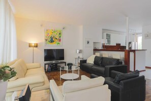 Ein modernes Wohnzimmer mit einem Flachbildfernseher, einem Couchtisch und zwei Sofas.