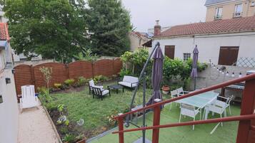 A backyard with a patio, outdoor furniture, a grill, and a garden.