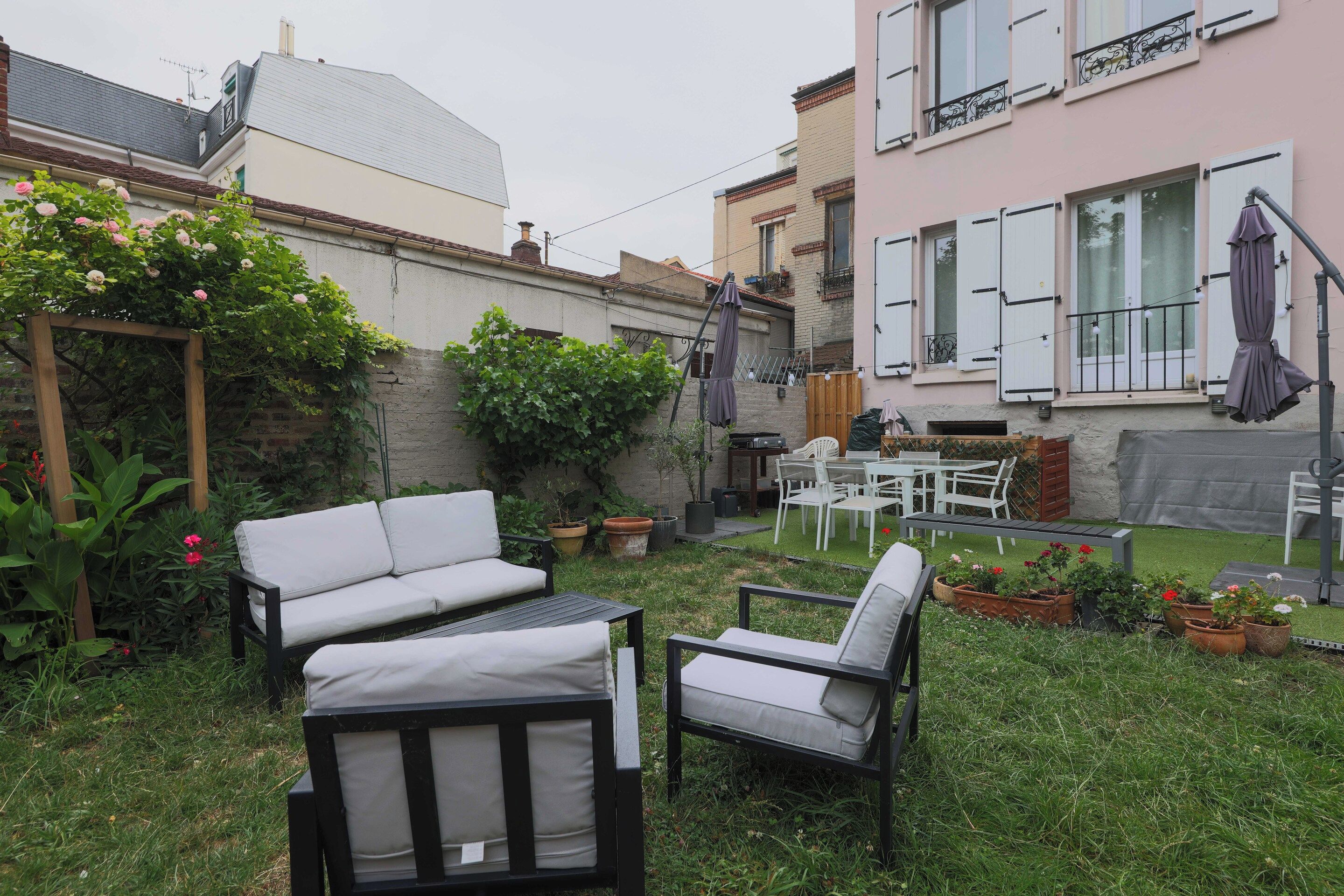 A patio area with outdoor furniture, including a sofa and chairs, surrounded by potted plants and a small garden.