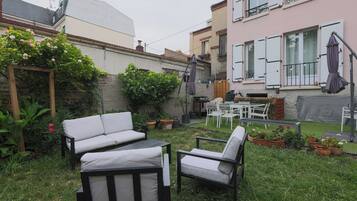 A patio area with outdoor furniture, including a sofa and chairs, surrounded by potted plants and a small garden.