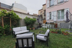 A patio area with outdoor furniture, including a sofa and chairs, surrounded by potted plants and a small garden. - House With Garden 4br/10p Near Paris (Le Kremlin-Bicetre)