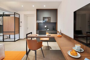 A modern kitchen with a coffee machine, a laptop on the table, and a dining area with a chair and a table.