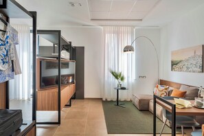 Uma sala de estar moderna com um sofá, uma mesa de jantar, um abajur e um quadro na parede.
