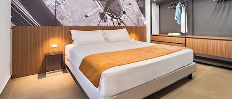 A modern hotel room with a large bed, a nightstand, a wooden headboard, and a wall-mounted TV.