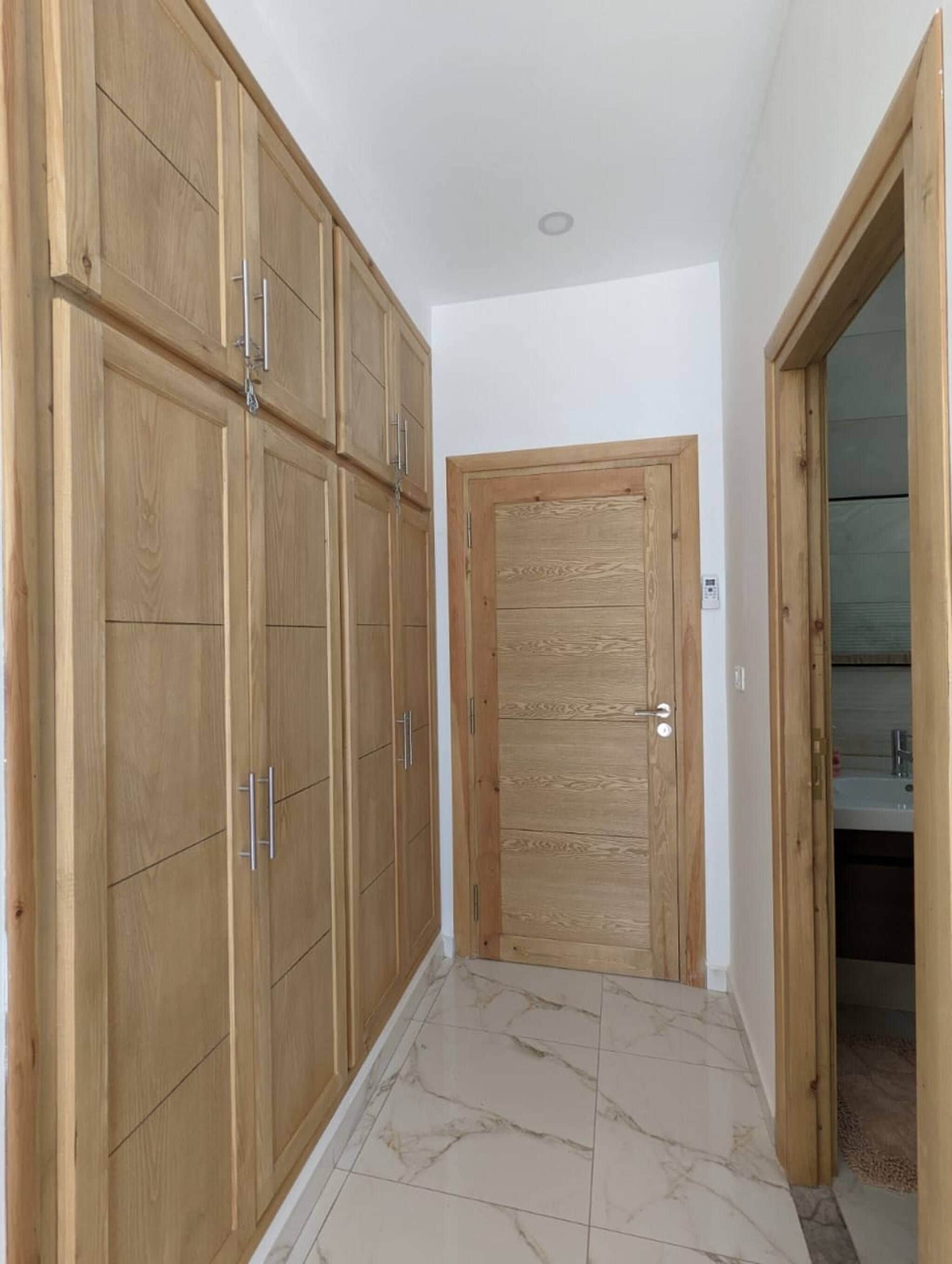 Un pasillo con armarios de madera y una puerta que da a un baño.