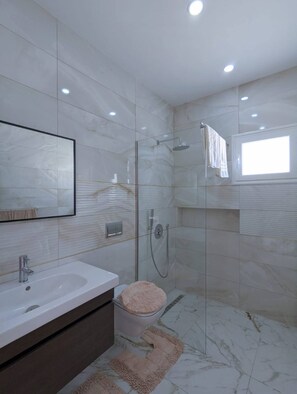 Un baño moderno con ducha envuelta en vidrio, un lavabo blanco y un inodoro con tapa rosa.